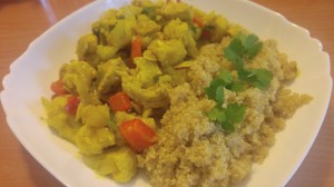 Cauliflower, bell pepper and chickpea curry, on a plate, with quinoa and coriander as garnish