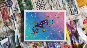 A painted colourful acrylic gecko on a canvas